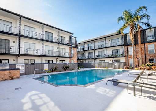 A pool in front of a building with a palm tree to the right.