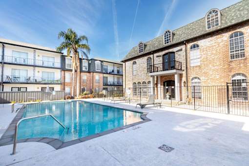 A swimming pool is surrounded by a fence and a building.