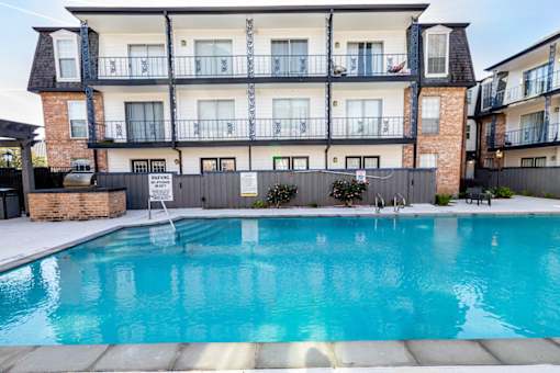 A large swimming pool in front of a multi-story apartment building.