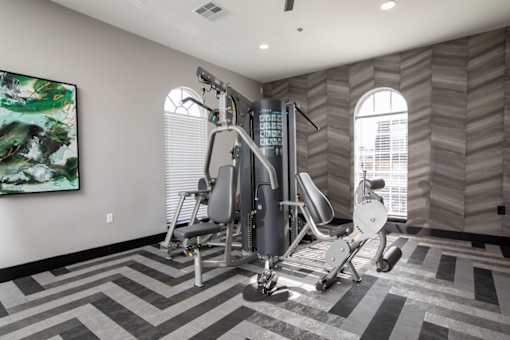A gym room with a treadmill, weights, and a painting.