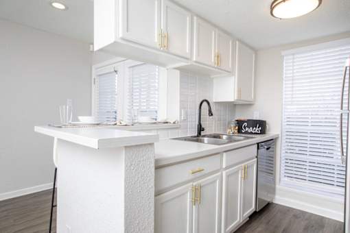 A kitchen with white cabinets and a white island with a sign that says snacks.