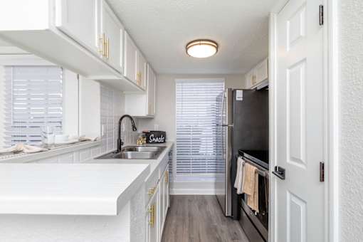 A kitchen with white cabinets and a black fridge.