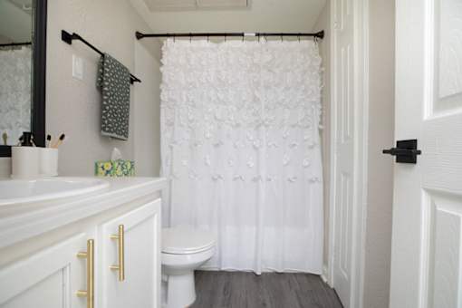 A white bathroom with a toilet, sink, and shower curtain.