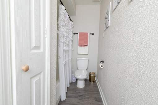 A white bathroom with a toilet, a towel, and a shower curtain.