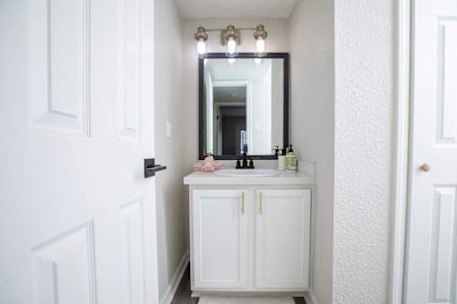 A white bathroom with a sink and mirror.