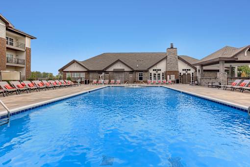 A large swimming pool in front of a building with a clear blue sky.