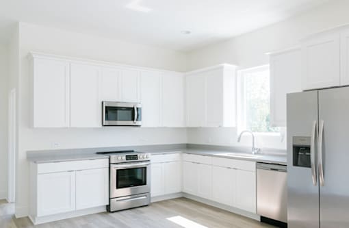 A modern kitchen with white cabinets and stainless steel appliances.at The Yarra, Tennessee