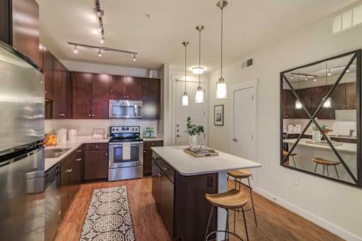 A modern kitchen with dark wood cabinets and stainless steel appliances.