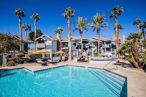 A swimming pool surrounded by palm trees and lounge chairs.