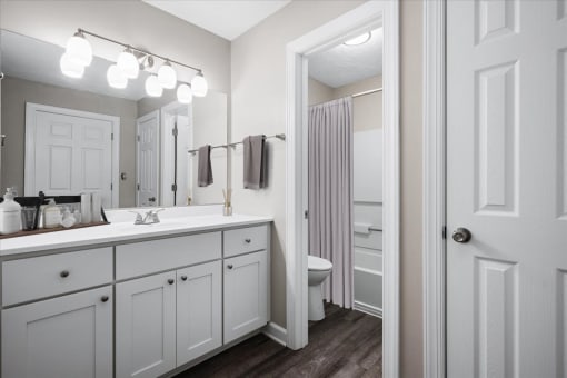 a bathroom with white cabinets and a white toilet next to a white sink