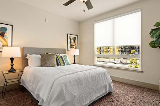 A bedroom with a large bed and a window overlooking a street.