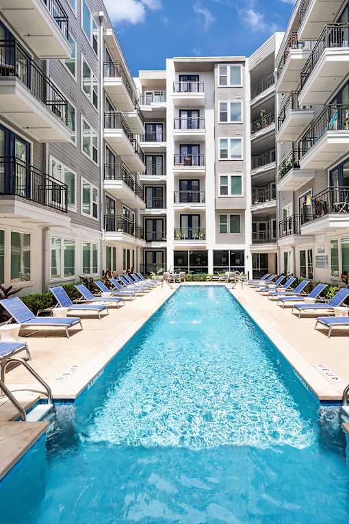 A large swimming pool in front of a multi-story residential building.