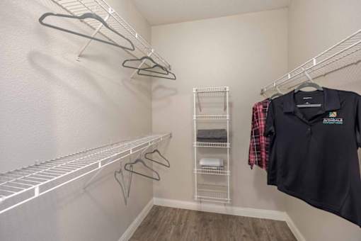 A black shirt hanging on a hanger in an oversized closet.