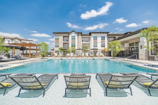 a swimming pool with lounge chairs and buildings in the background
