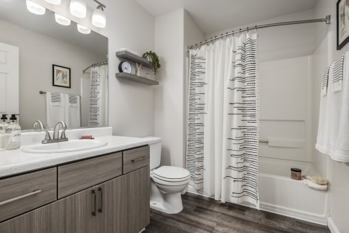 Bathroom with white countertop and striped shower curtain at Canyon Creek Apartments, Wilsonville, OR 97070