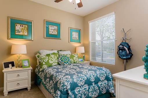 A bedroom with a bed, nightstand, and three pictures on the wall.