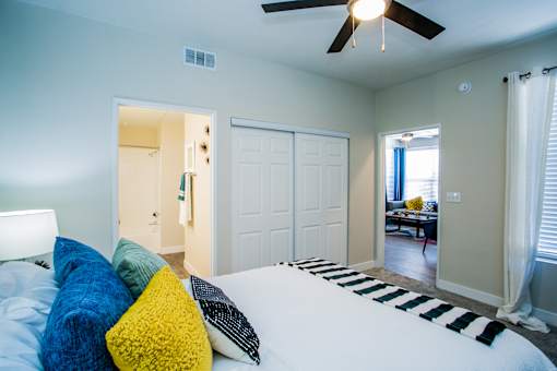 A bedroom with a bed, pillows, and a ceiling fan.