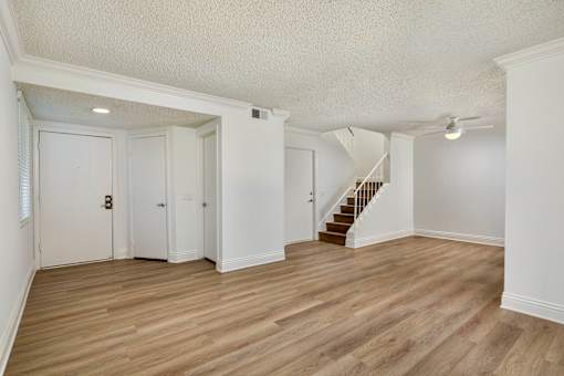 A spacious living room with wooden floors and white walls.