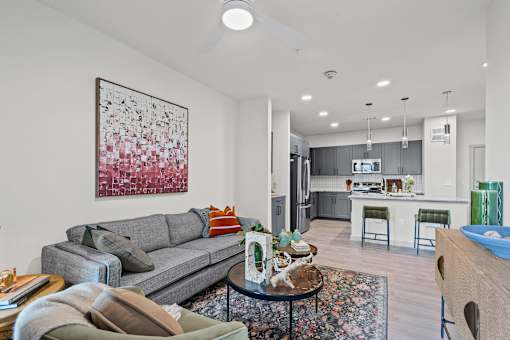 A living room with a grey couch and a painting on the wall.