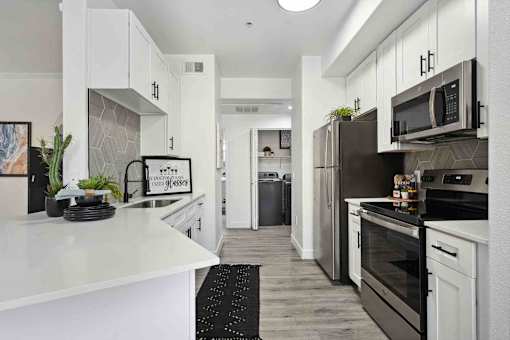 A modern kitchen with white cabinets and stainless steel appliances.