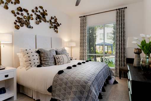 A bedroom with a bed, pillows, and a ceiling fan.