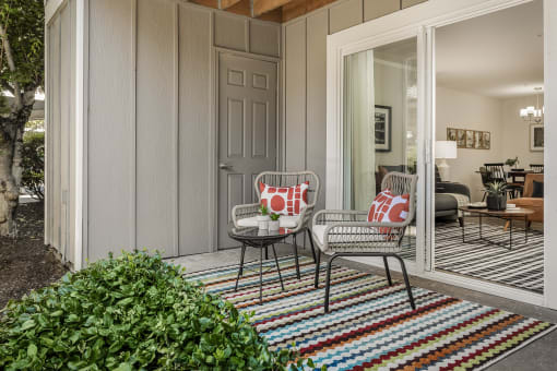 Covered patio seating area with colorful striped rug at Canyon Creek Apartments, Wilsonville, OR