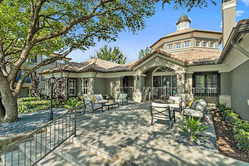 A large house with a patio and a tree in front.