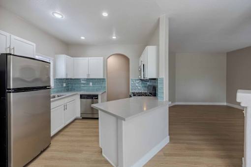 A kitchen with white cabinets and a stainless steel refrigerator.