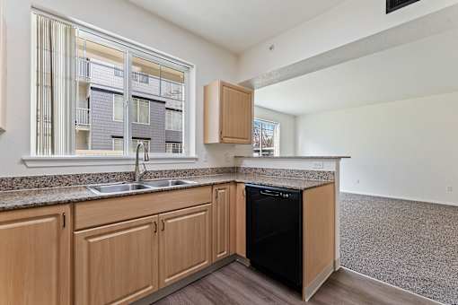 A kitchen with wooden cabinets and a black dishwasher.