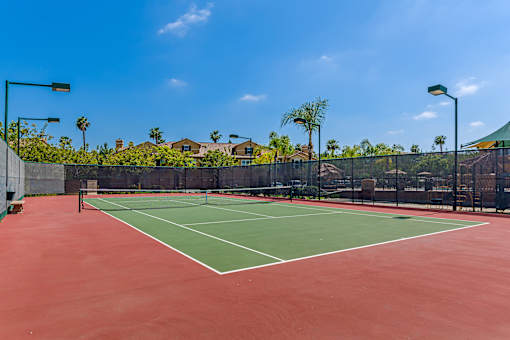 A tennis court with a red surface and green boundary lines.