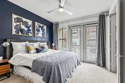 A bedroom with a bed, a ceiling fan, and a window with blinds.