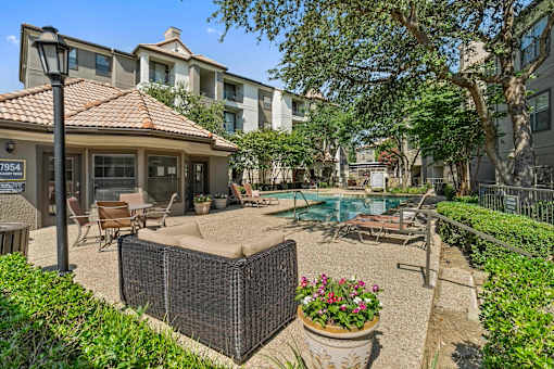A patio with a pool and a building in the background.