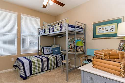 A room with a bed, a desk, and a fan.