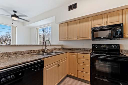 A kitchen with black appliances and wooden cabinets.