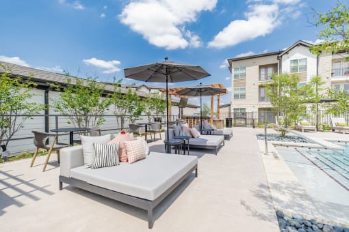 an outdoor patio with couches and umbrellas and a pool
