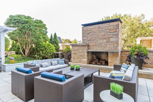 a patio with wicker furniture and a stone fireplace