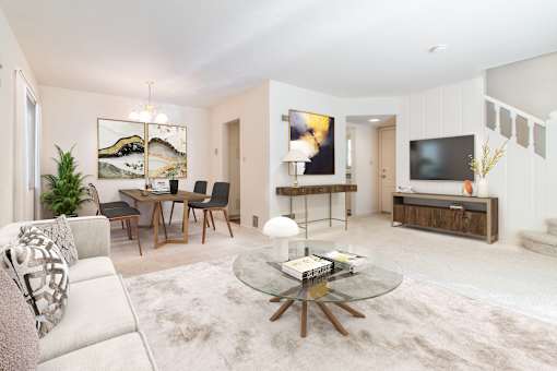 A modern living room with a glass coffee table and a white sofa.