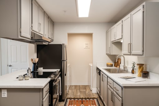 Galley kitchen with white counters and pendant lighting at Canyon Creek Apartments, Wilsonville, Oregon