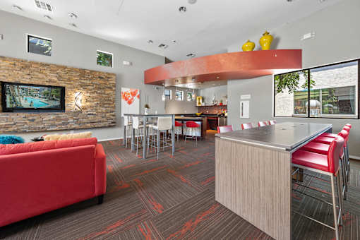 A modern office space with a red couch, a stone wall, and a television.