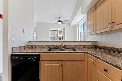 A kitchen with wooden cabinets and a black dishwasher.