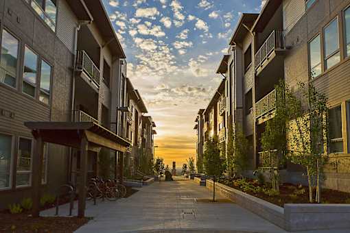 A sunset view of a street lined with modern apartment buildings.