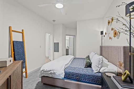 A bedroom with a bed, a mirror, and a ceiling fan.