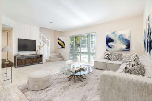 A modern living room with a glass coffee table and a white couch.