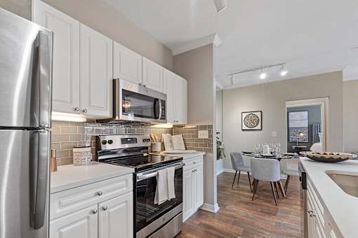 A modern kitchen with white cabinets and stainless steel appliances.