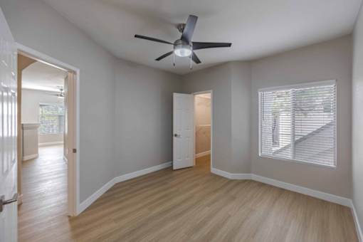 A room with a ceiling fan and a window with blinds.