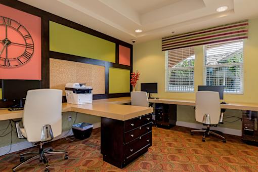 A room with a desk and chairs and a clock on the wall.