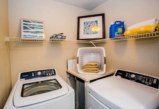 A laundry room with a washer and dryer and a basket of towels.