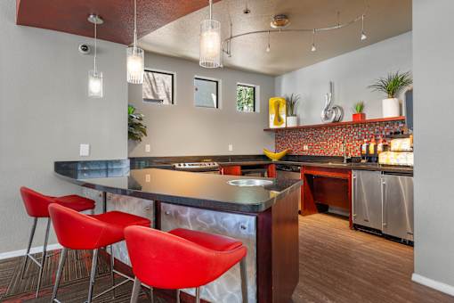 A kitchen with a bar area and red chairs.