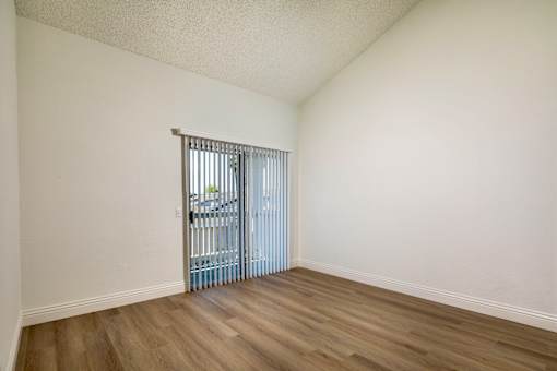 A bedroom with high ceilings, a sliding door and wooden flooring.
