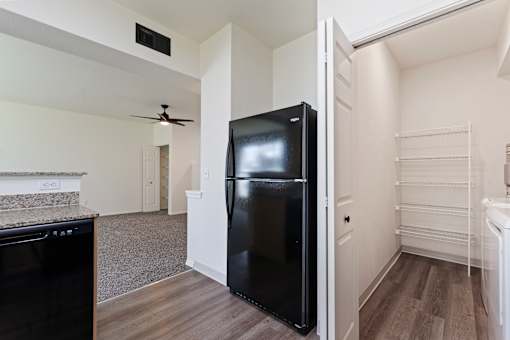 A black refrigerator in a kitchen with a fan on the ceiling.